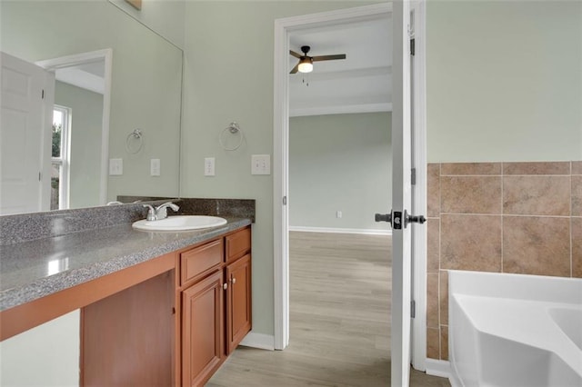 bathroom featuring a bathtub, tile walls, vanity, ceiling fan, and hardwood / wood-style floors