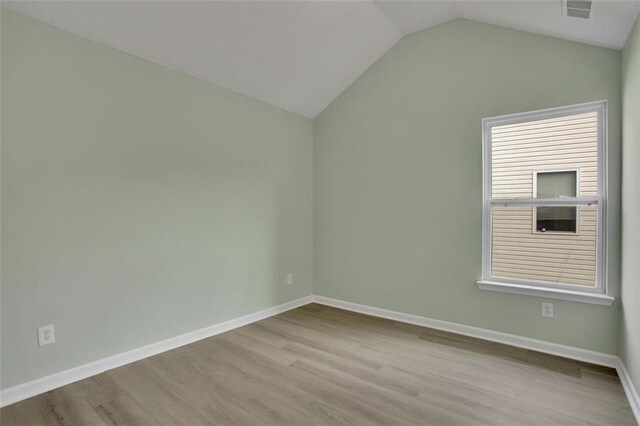 spare room featuring light wood-type flooring and lofted ceiling