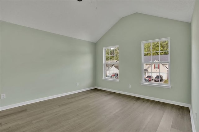 spare room with light wood-type flooring, lofted ceiling, and ceiling fan