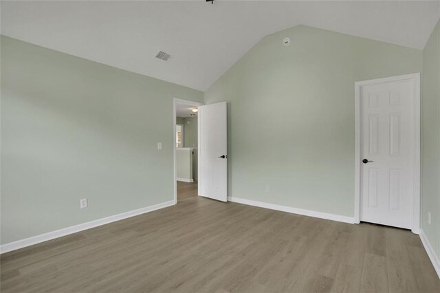 spare room featuring light hardwood / wood-style flooring and lofted ceiling