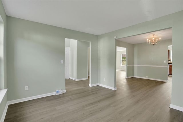 unfurnished room with wood-type flooring and a notable chandelier