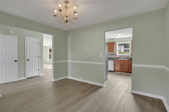 unfurnished room featuring light hardwood / wood-style flooring, a chandelier, and sink