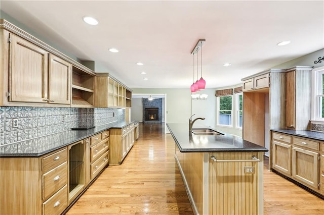 8464 Pleasant Hill Rd, Lithonia, GA 30058 - kitchen featuring dark countertops, a sink, light wood finished floors, open shelves, and an island with sink