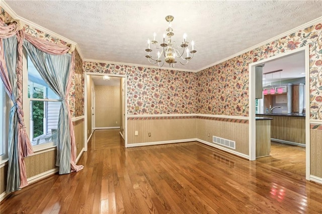 8464 Pleasant Hill Rd, Lithonia, GA 30058 - unfurnished dining area featuring a wainscoted wall, a chandelier, crown molding, hardwood / wood-style flooring, and a textured ceiling