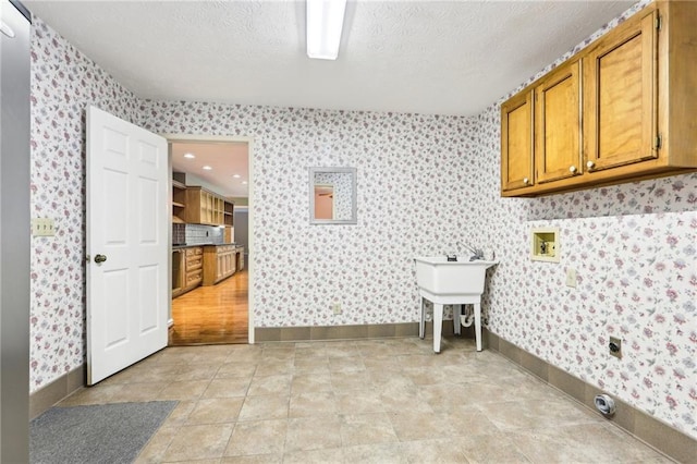 8464 Pleasant Hill Rd, Lithonia, GA 30058 - laundry room featuring cabinet space, washer hookup, wallpapered walls, a textured ceiling, and baseboards