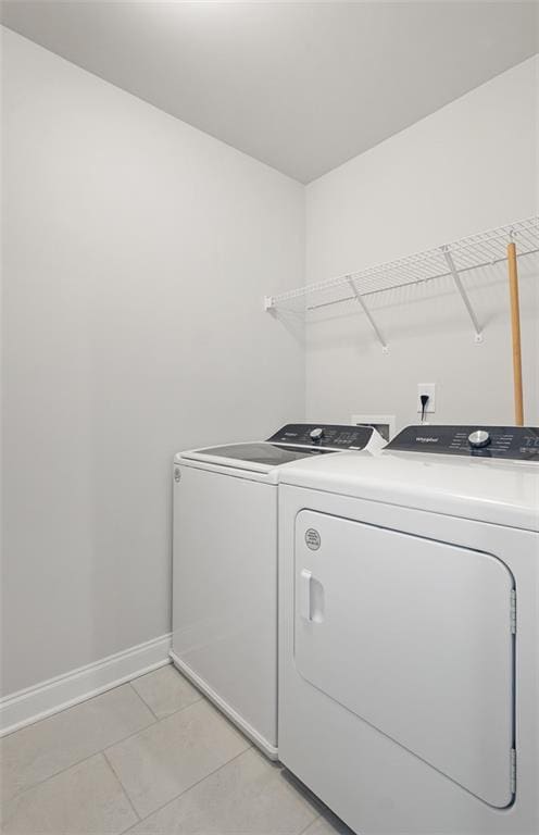 clothes washing area with light tile patterned floors and washing machine and dryer