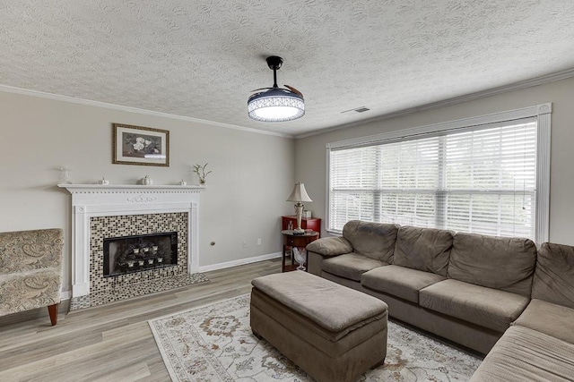 living room with a tiled fireplace, hardwood / wood-style flooring, a wealth of natural light, and ornamental molding