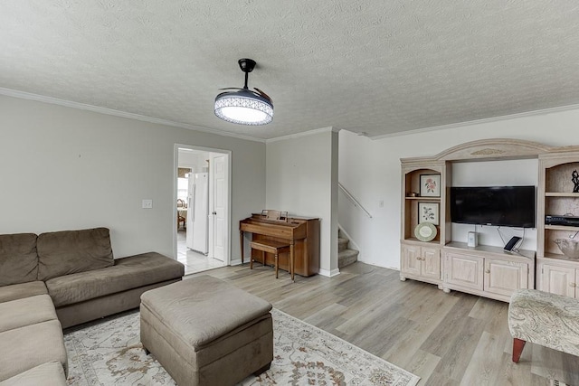 living room with ornamental molding, light hardwood / wood-style flooring, and a textured ceiling