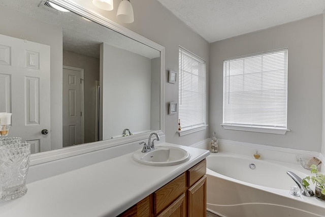 bathroom with vanity, a tub to relax in, and a textured ceiling