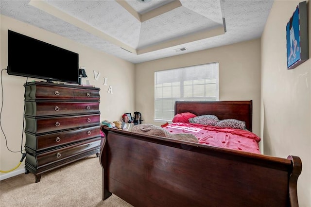 bedroom with carpet flooring, visible vents, a textured ceiling, and a tray ceiling