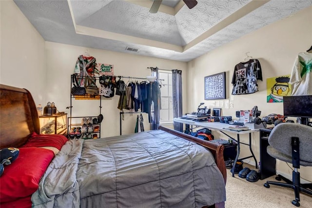 bedroom with a raised ceiling, carpet flooring, a ceiling fan, and a textured ceiling