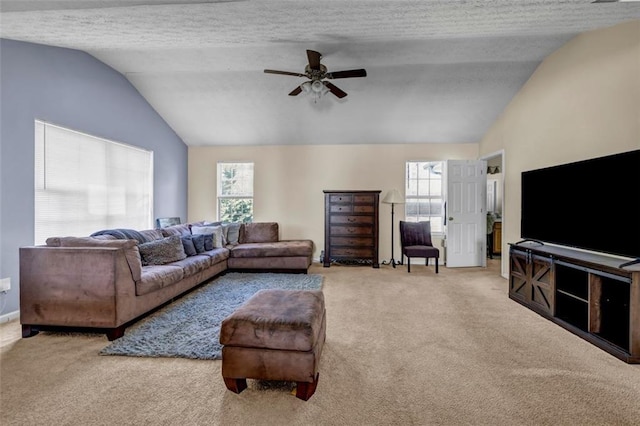 carpeted living area featuring a textured ceiling, lofted ceiling, a healthy amount of sunlight, and ceiling fan