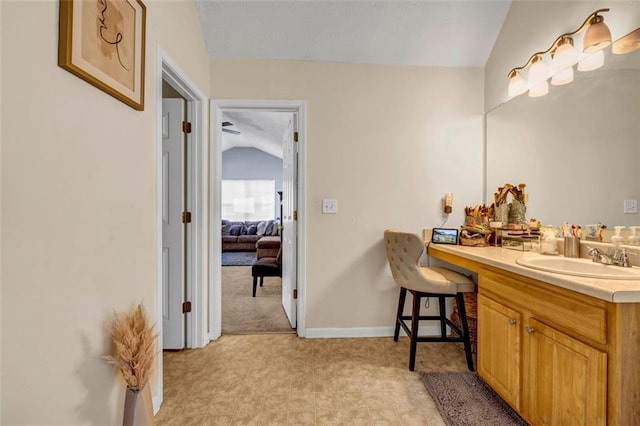 bathroom with vanity, vaulted ceiling, and baseboards