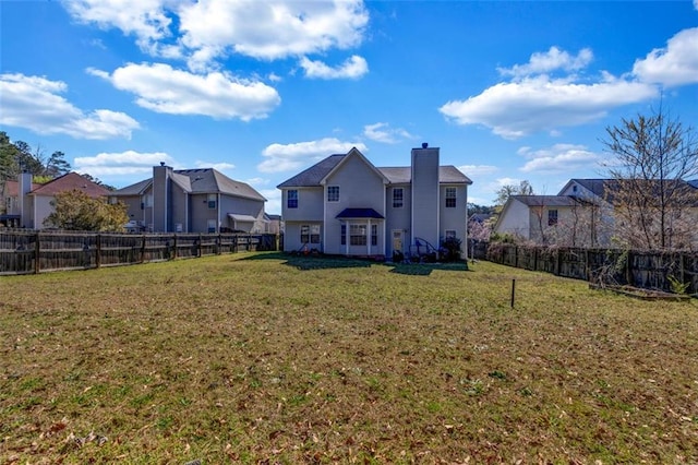 back of property with a lawn, a fenced backyard, and a chimney