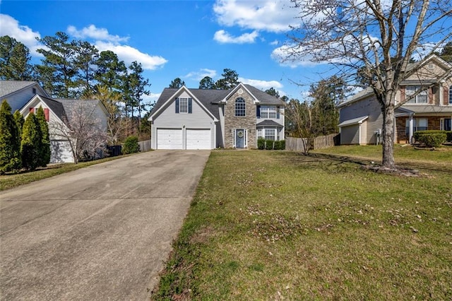 traditional-style house with concrete driveway, a garage, fence, and a front lawn