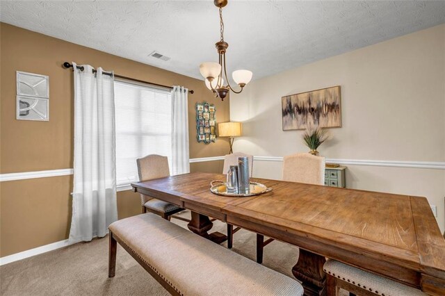 dining area with visible vents, a textured ceiling, baseboards, light colored carpet, and a chandelier