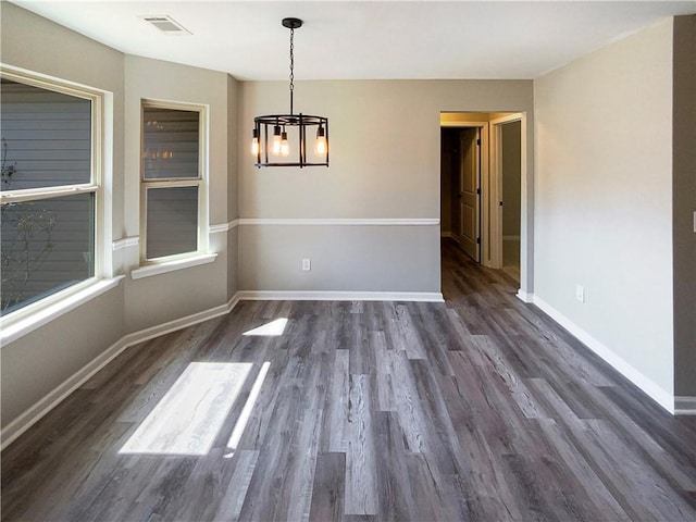 unfurnished dining area featuring a chandelier, dark wood-style flooring, visible vents, and baseboards