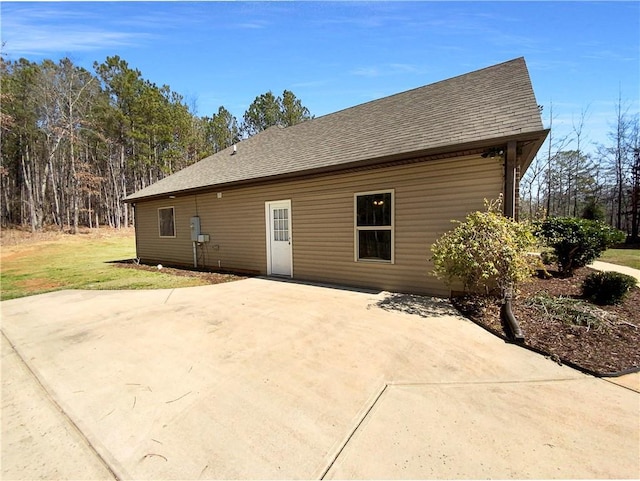 rear view of house featuring driveway and a shingled roof