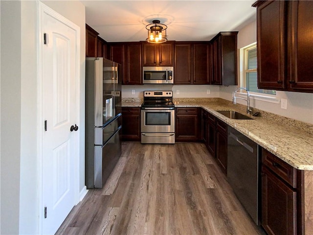 kitchen featuring stainless steel appliances, light stone counters, dark wood-style flooring, and a sink