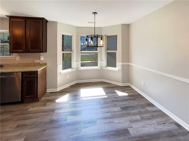 unfurnished dining area featuring a chandelier, dark wood-type flooring, and baseboards