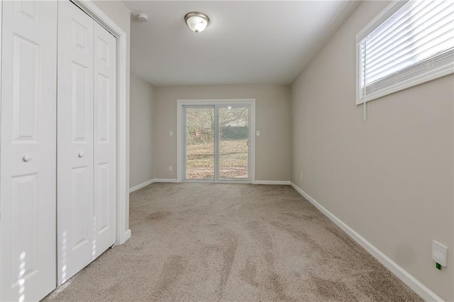 unfurnished bedroom featuring a closet, light carpet, and multiple windows