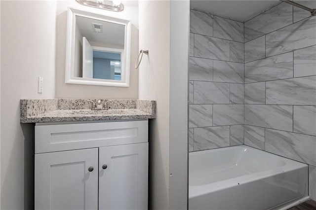 bathroom featuring tiled shower / bath combo and vanity