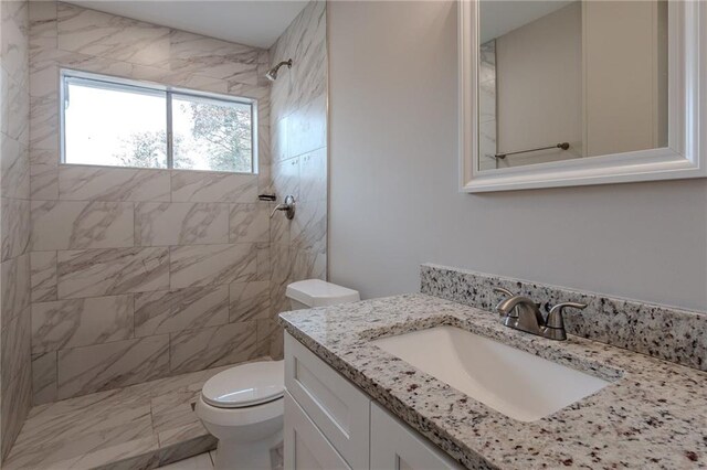 bathroom featuring vanity, toilet, and a tile shower