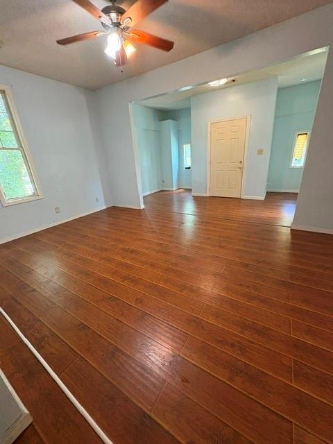 spare room featuring wood-type flooring, ceiling fan, and baseboards