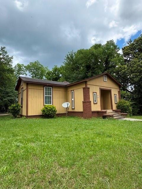 view of front facade featuring a front lawn and view of wooded area