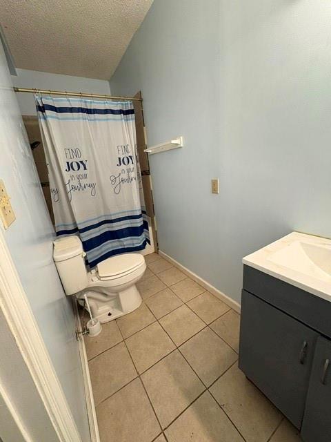full bathroom with a textured ceiling, tile patterned floors, toilet, vanity, and baseboards