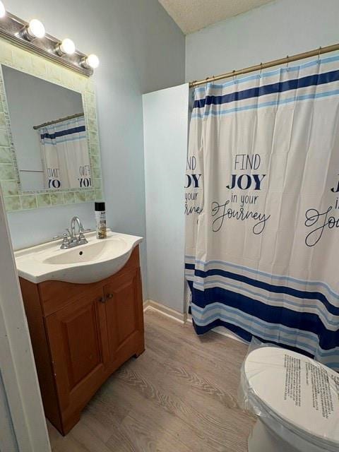full bath featuring wood finished floors, vanity, toilet, curtained shower, and a textured ceiling