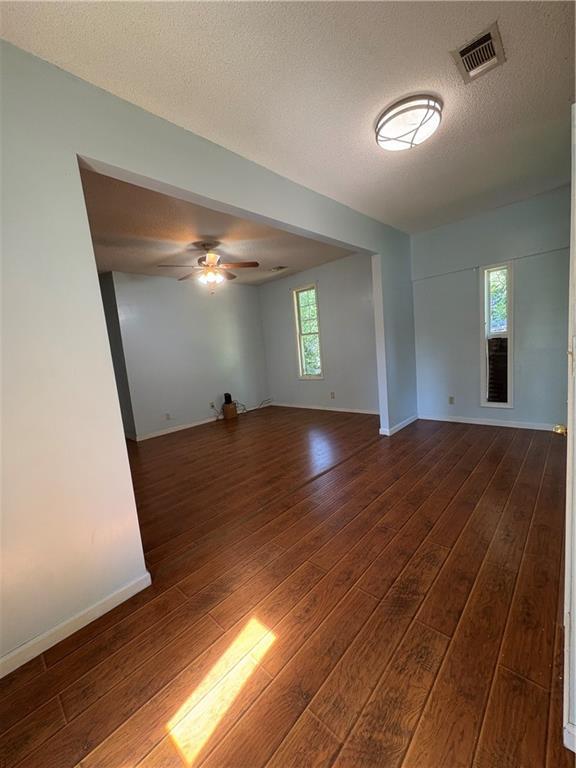 3831 Fairmont Ave, Macon, GA 31204 - empty room with dark wood-type flooring, a ceiling fan, a textured ceiling, and baseboards