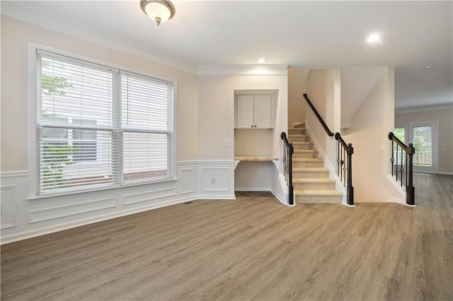 3382 Galleon Dr, Alpharetta, GA 30004 - unfurnished living room with crown molding, stairway, light wood-style flooring, wainscoting, and a decorative wall