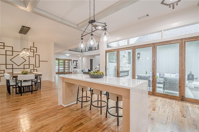 1273 Grayson Pkwy, Grayson, GA 30017 - kitchen featuring light wood finished floors, open floor plan, decorative light fixtures, and a breakfast bar