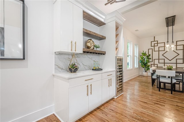 1273 Grayson Pkwy, Grayson, GA 30017 - indoor dry bar with light wood finished floors, baseboards, backsplash, wine cooler, and decorative light fixtures