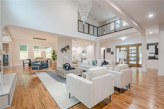 1273 Grayson Pkwy, Grayson, GA 30017 - living room with a chandelier, light wood-style flooring, a high ceiling, baseboards, and arched walkways