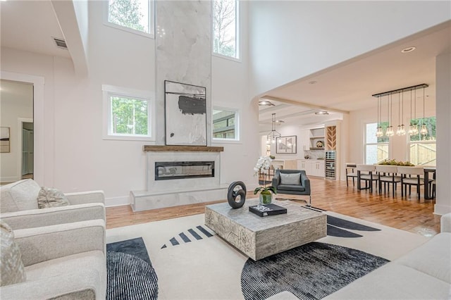1273 Grayson Pkwy, Grayson, GA 30017 - living area featuring a premium fireplace, a towering ceiling, a chandelier, wood finished floors, and baseboards