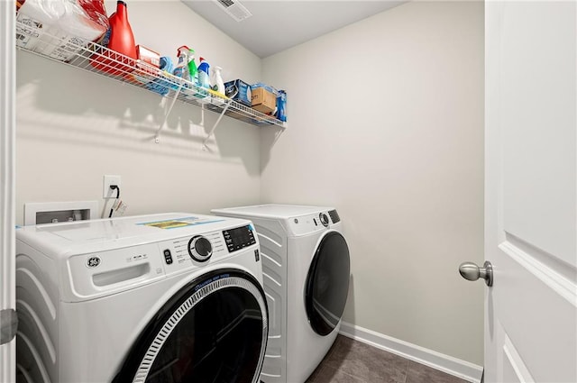 laundry room with washing machine and dryer, laundry area, dark tile patterned floors, visible vents, and baseboards