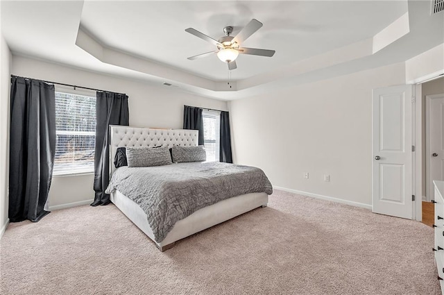 bedroom featuring carpet floors, a tray ceiling, visible vents, and baseboards