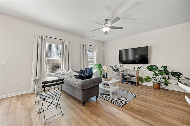 living area featuring light wood-type flooring, ceiling fan, and baseboards