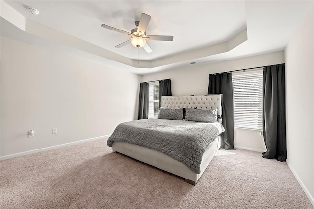 bedroom featuring ceiling fan, carpet floors, a tray ceiling, and baseboards