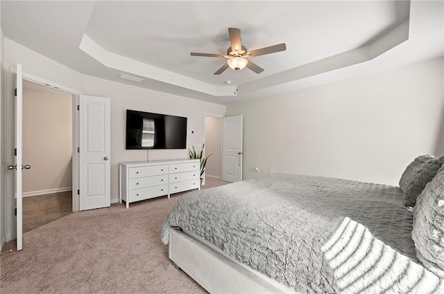 bedroom featuring a ceiling fan, a raised ceiling, and carpet flooring