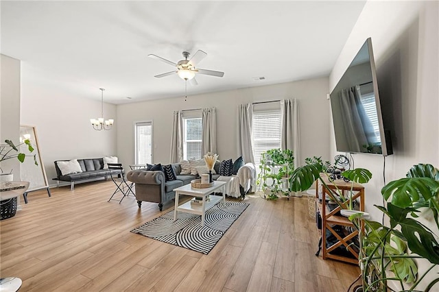 living room featuring visible vents, light wood-style flooring, and ceiling fan with notable chandelier