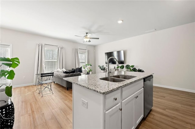 kitchen with stainless steel dishwasher, light wood-style floors, open floor plan, a sink, and an island with sink