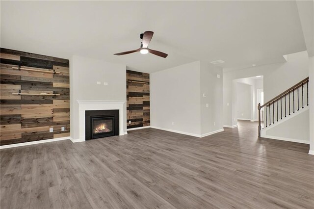 56 Preserve Pt, Jasper, GA 30143 - unfurnished living room featuring a ceiling fan, a glass covered fireplace, stairway, wood finished floors, and wooden walls