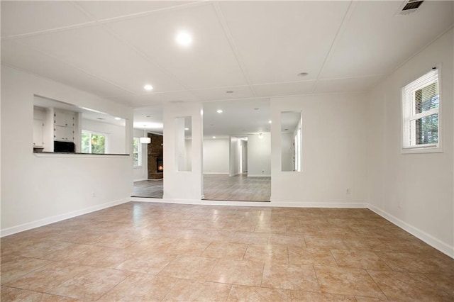 spare room featuring baseboards, visible vents, a lit fireplace, and recessed lighting
