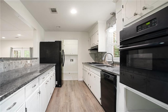 kitchen featuring white cabinets, black appliances, backsplash, a sink, and visible vents