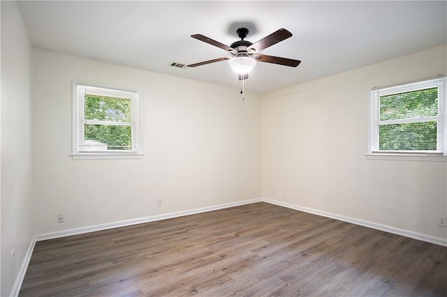 spare room featuring baseboards, visible vents, wood finished floors, and a ceiling fan
