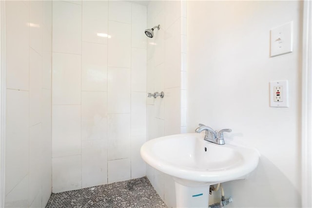 bathroom with tiled shower, tile patterned flooring, and a sink
