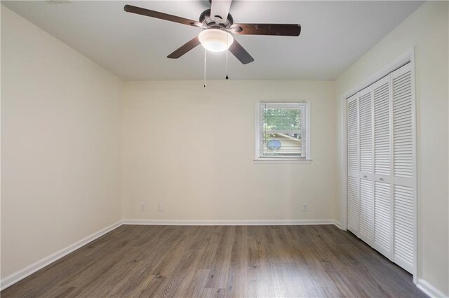 unfurnished bedroom featuring a closet, a ceiling fan, wood finished floors, and baseboards